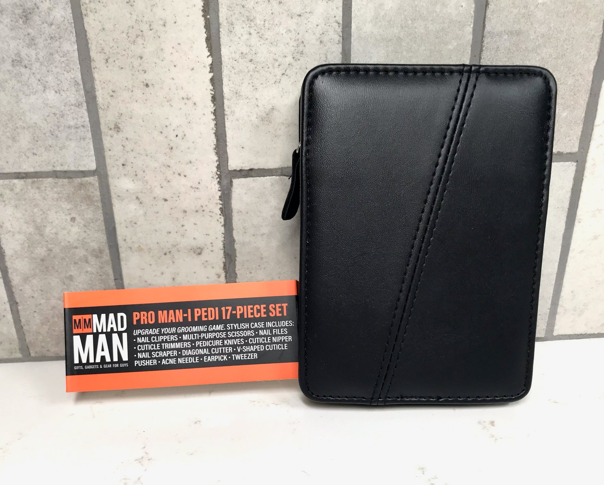 Black leather case next to a box labeled 'MAD MAN' on a tiled floor.