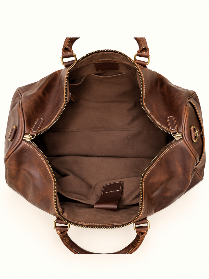 Overhead view of the Dusty Duffel brown leather travel bag showing its spacious fabric-lined interior, interior pocket, and wide zippered opening.