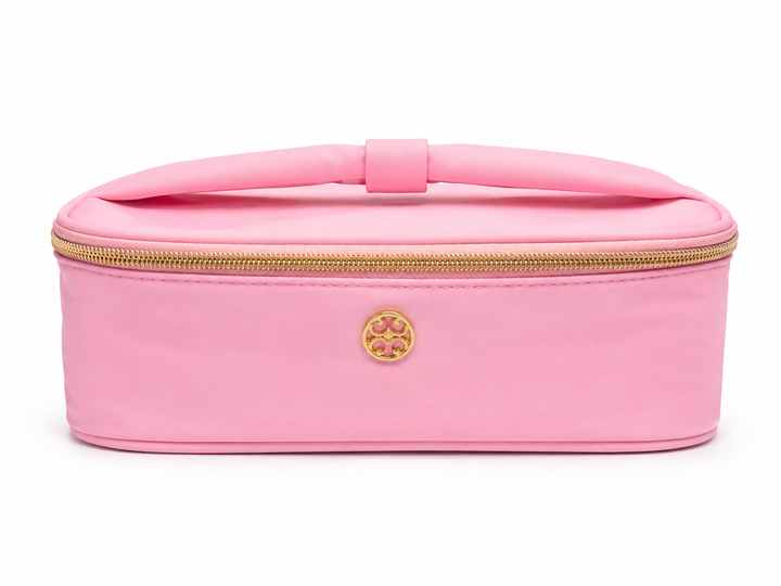 Pink cosmetic travel case with gold zipper, top handle, and structured design for makeup, toiletries, and beauty essentials.