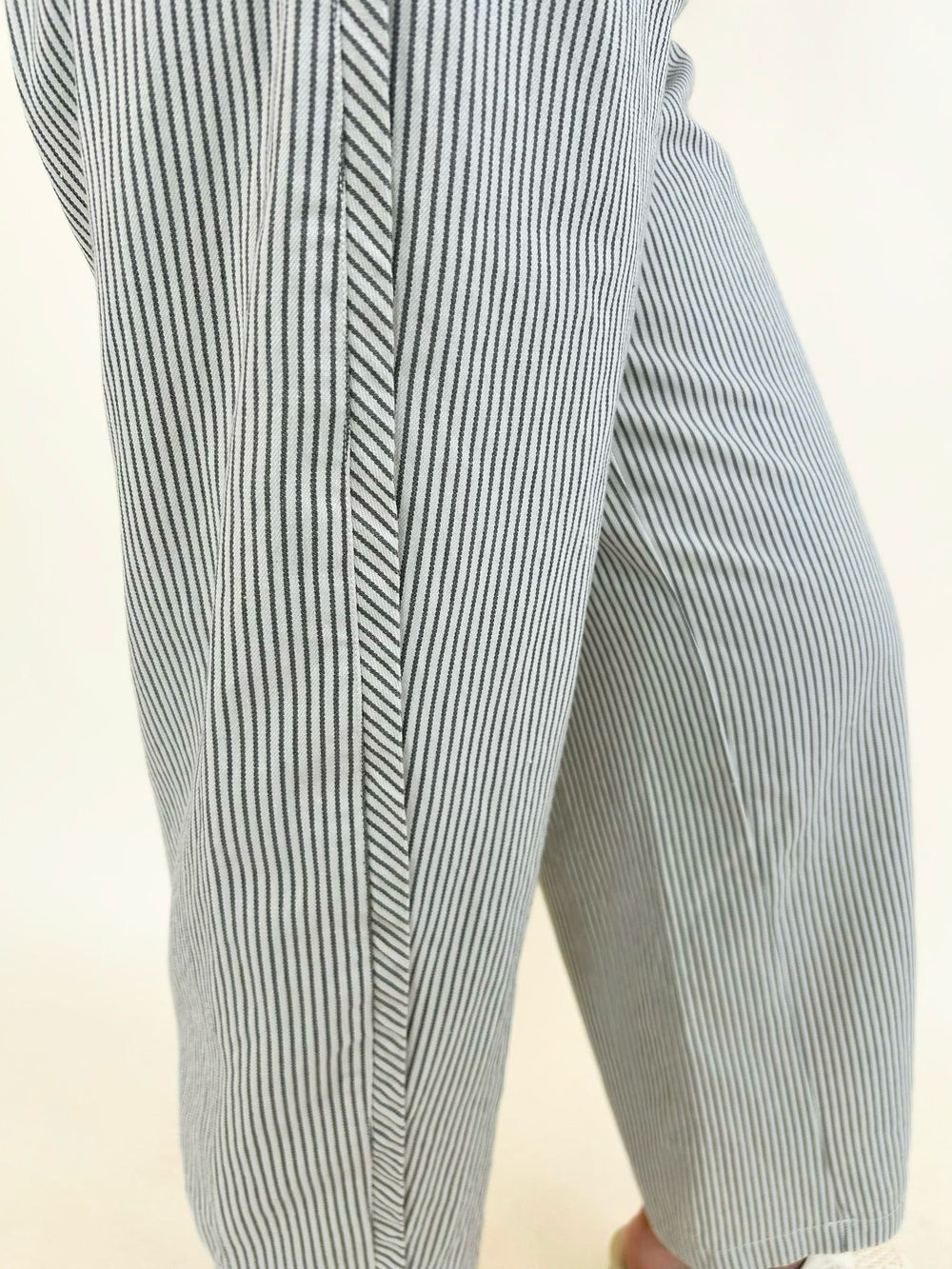Close-up of women's green and white pinstripe pants highlighting the lightweight fabric, relaxed wide-leg fit, and subtle vertical stripe pattern.