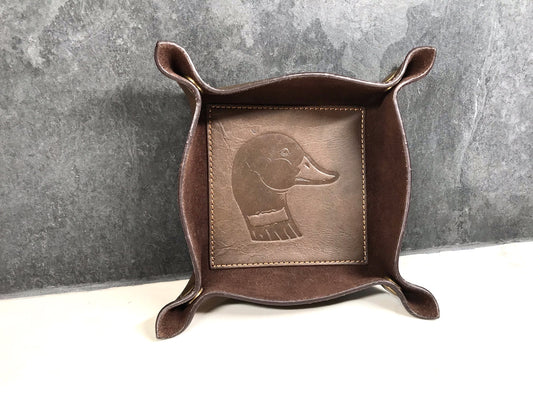 Brown leather tray with embossed dog design on a gray background