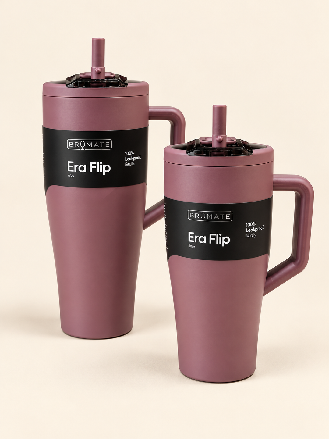 BrüMate Era Flip 40oz and 30oz insulated tumblers in matte mauve pink with matching handles, flip straw lids, and black branded labels displayed together on a cream studio background.