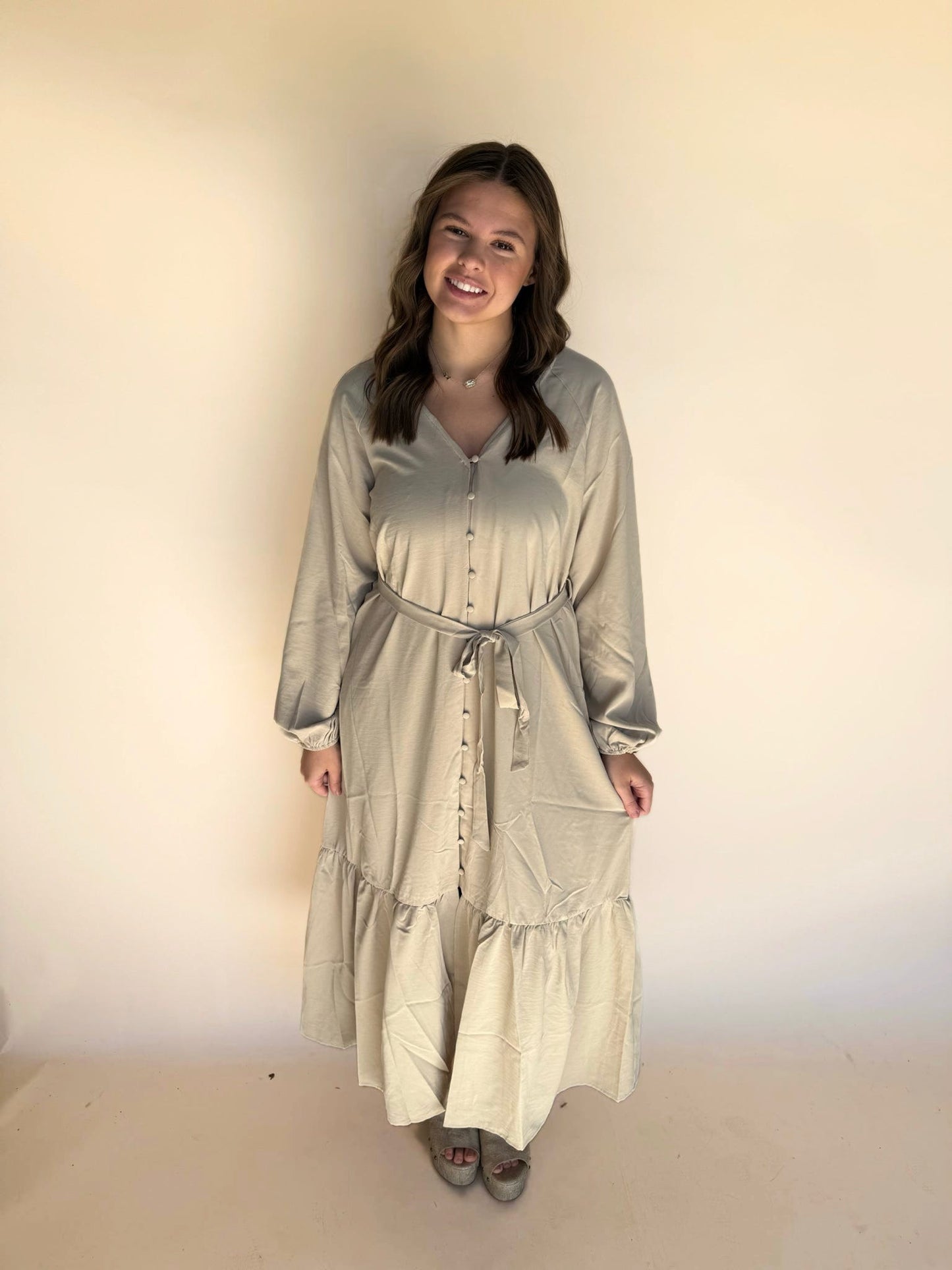 Woman wearing a long, light-colored dress against a plain background