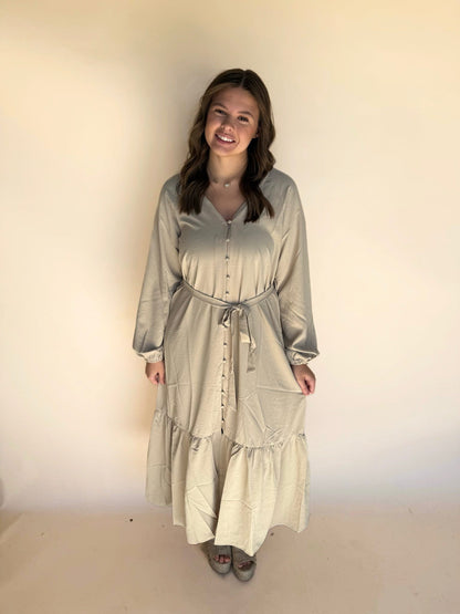 Woman wearing a long, light-colored dress against a plain background