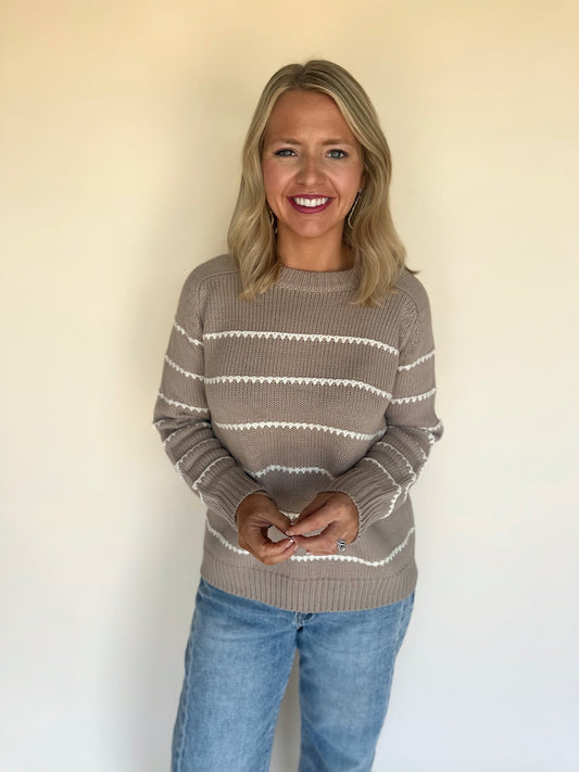 Woman wearing a striped sweater and jeans against a plain background