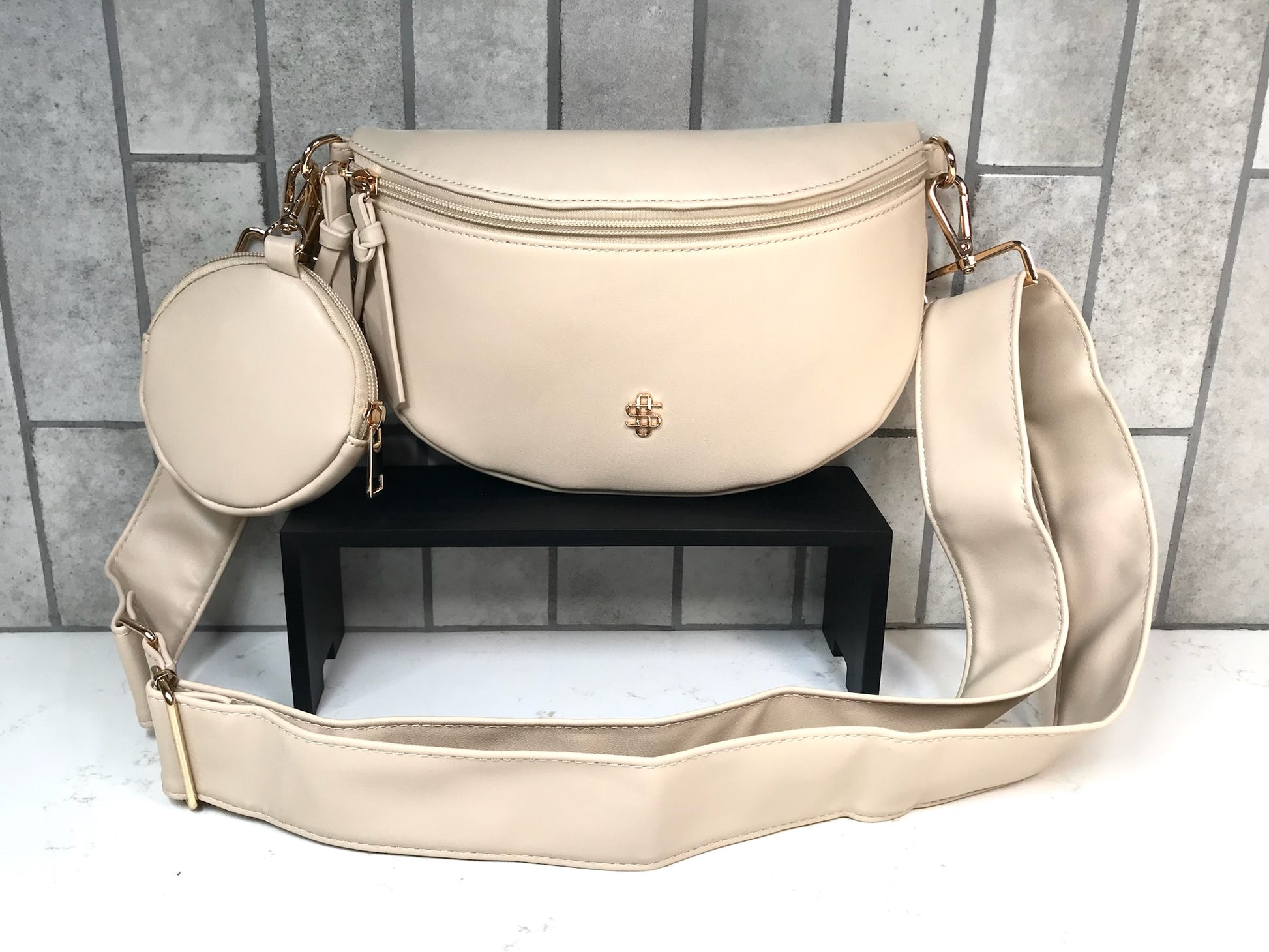 Beige handbag with a smaller round bag on a gray tiled background