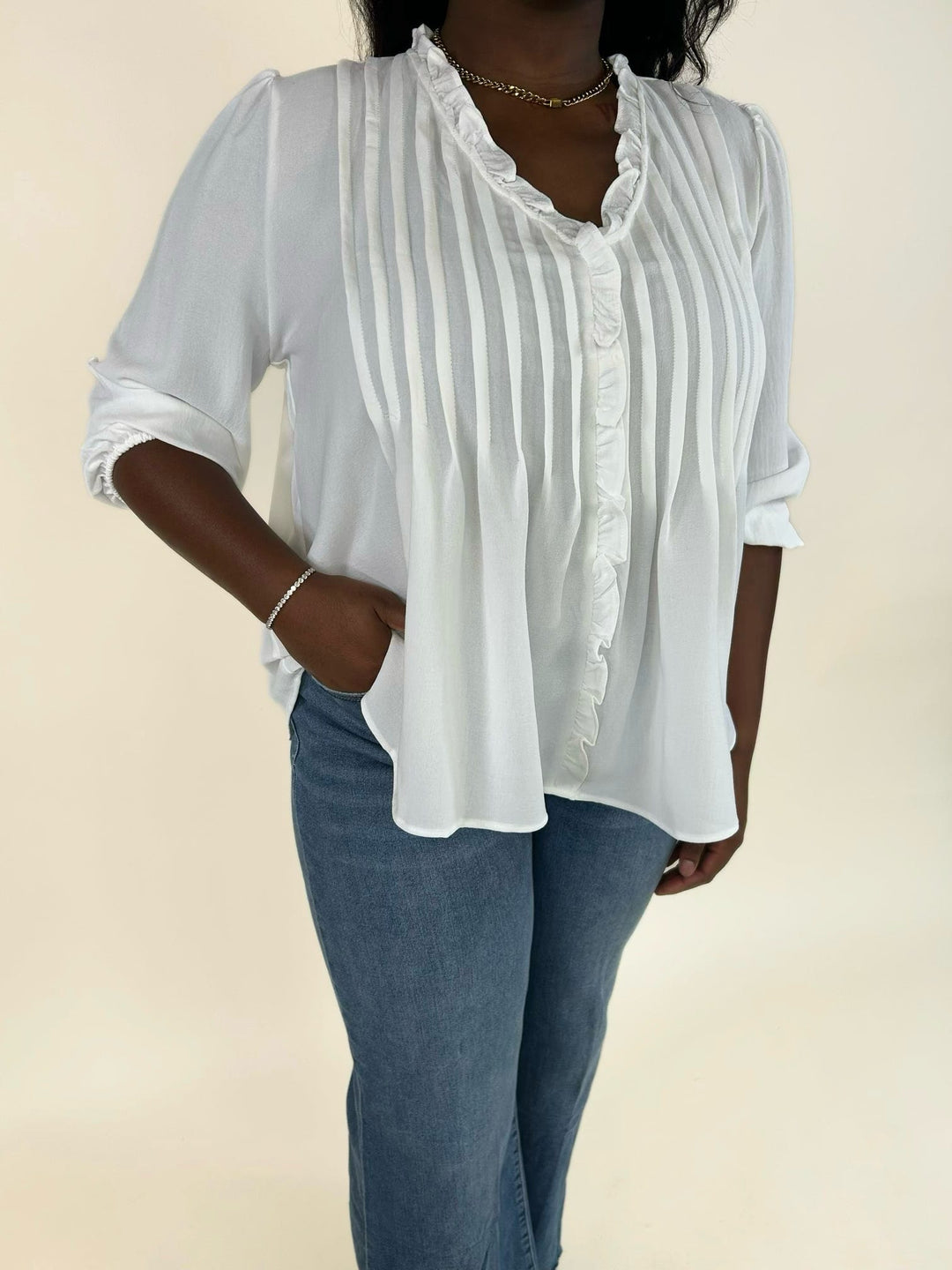 Side view of the white 3/4 sleeve ruffle trim blouse styled with blue jeans.