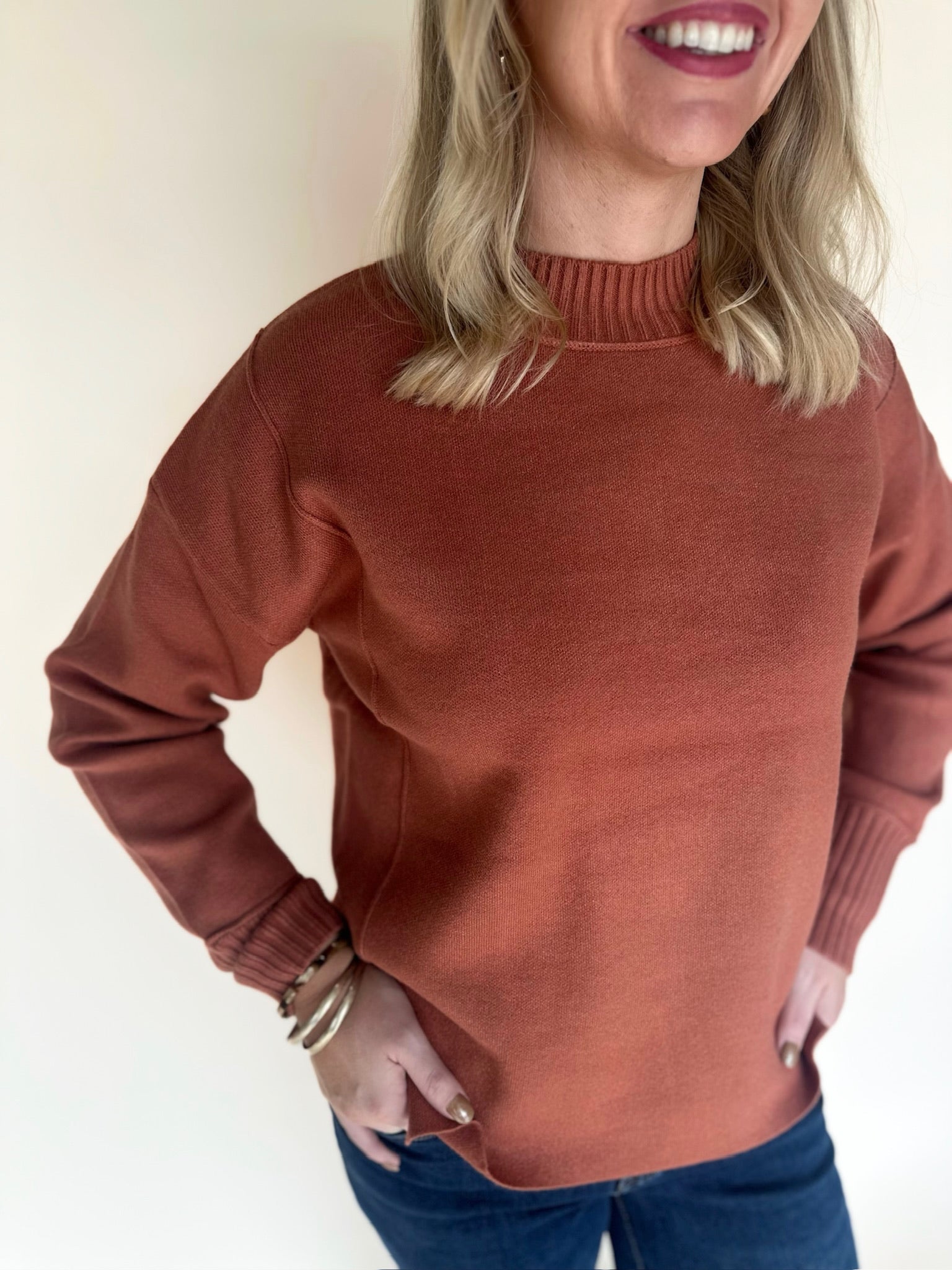 Woman wearing a copper sweater against a plain background