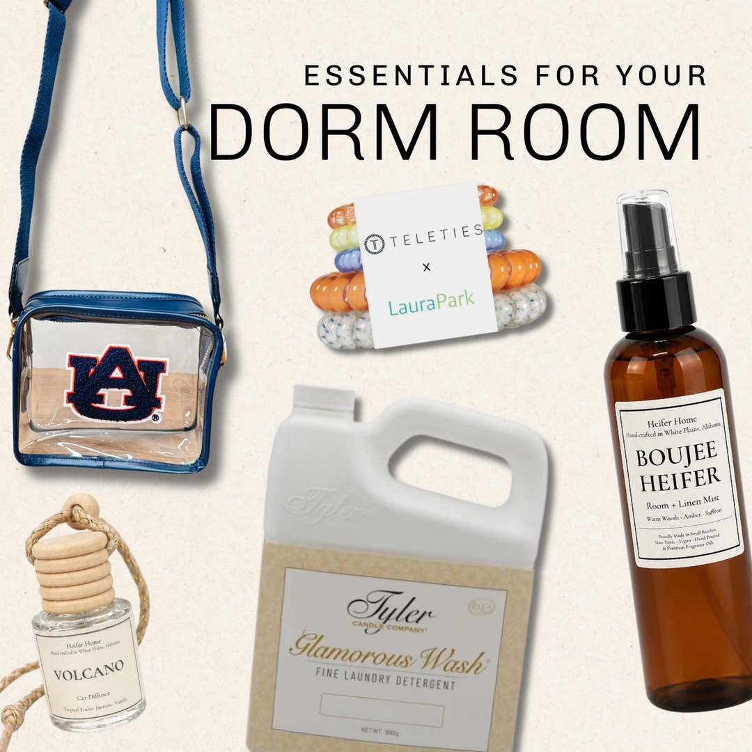 A curated dorm room essentials bundle featuring a blue and clear Auburn Tigers crossbody bag, a Teleties x Laura Park bracelet, a bottle of Houler House Boujee Heifer room spray, a Taylor laundry detergent jug, and a Volcano diffuser, all arranged on a light beige background with the text 'ESSENTIALS FOR YOUR DORM ROOM' | Square 1 Boutique | Brent, AL