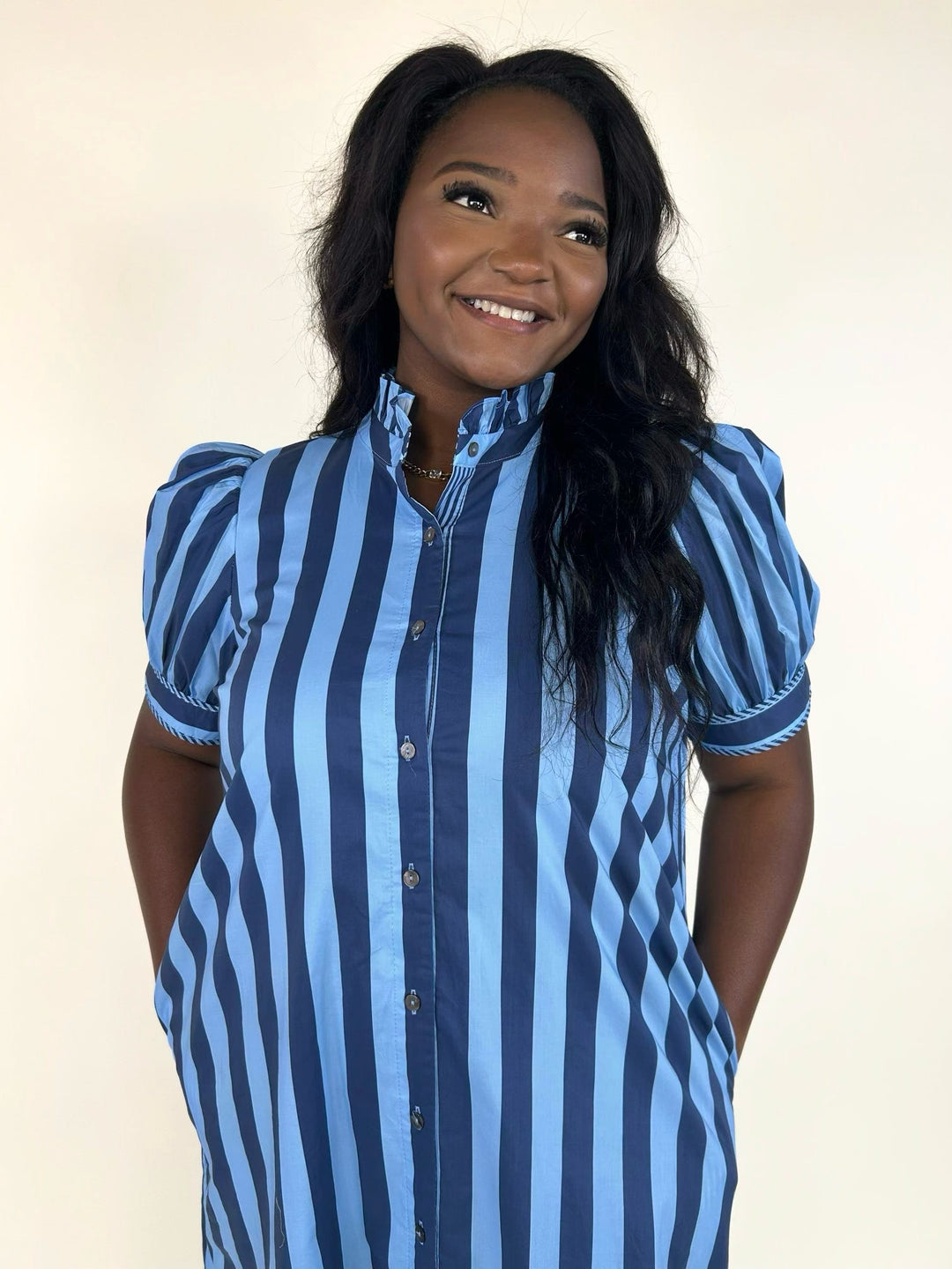 Close-up of the blue striped midi shirt dress featuring a ruffled mock neckline, functional button front, and puff sleeves with decorative trim.