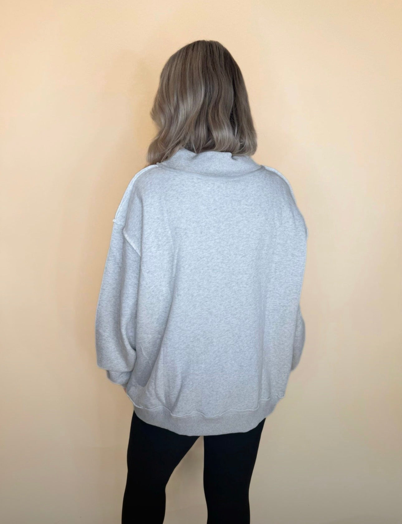 Back view of oversized light gray sweatshirt paired with black leggings, relaxed loose fit and drop shoulder seams.