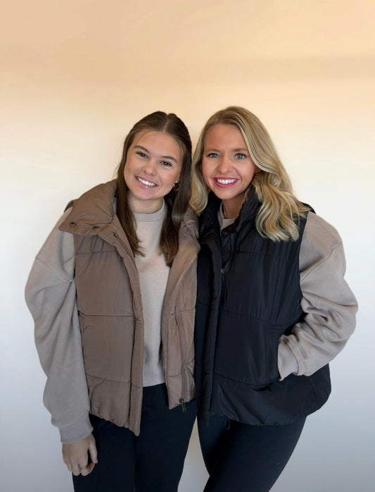 Two women standing side by side wearing matching jackets against a plain background