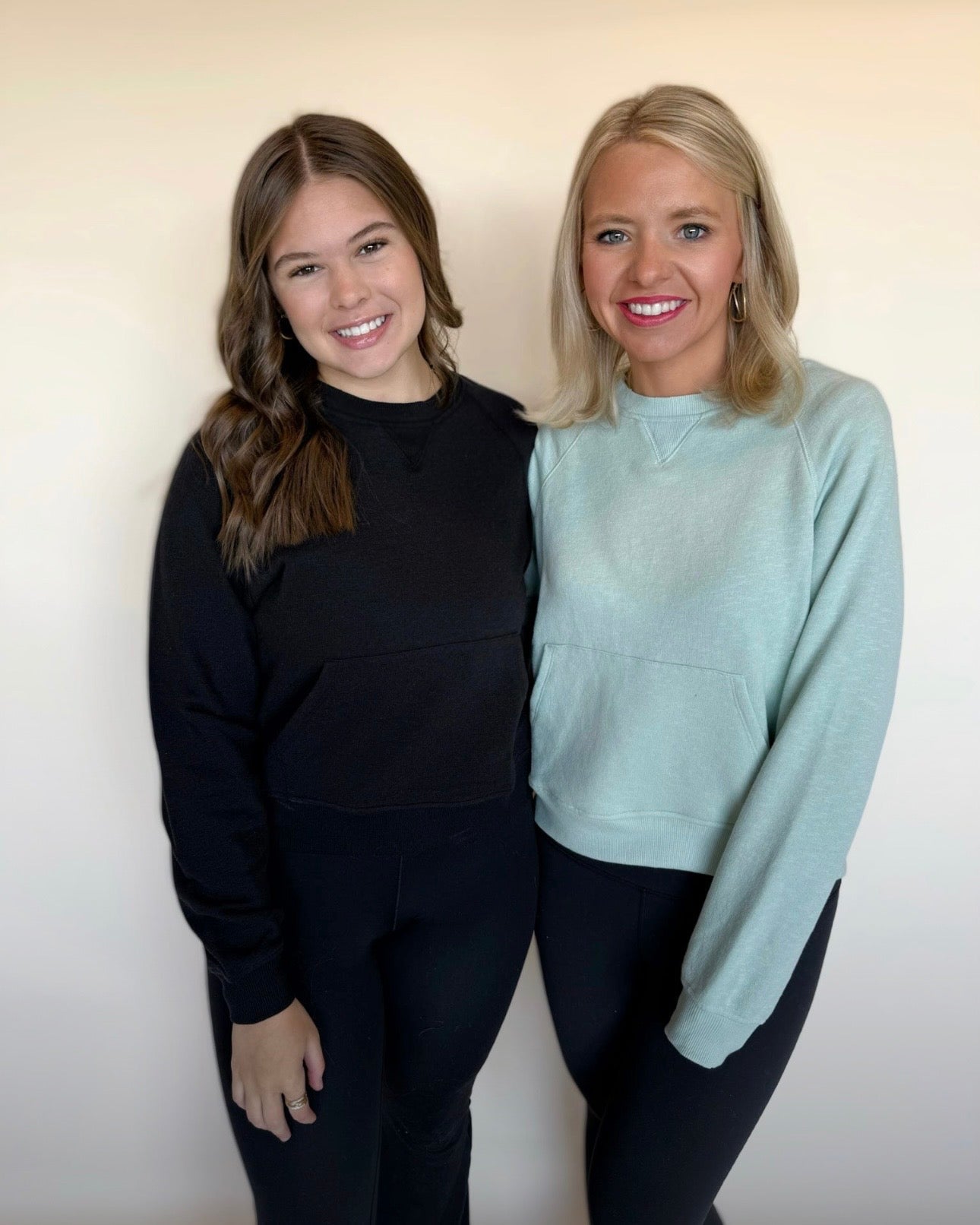 Two women standing side by side against a plain background