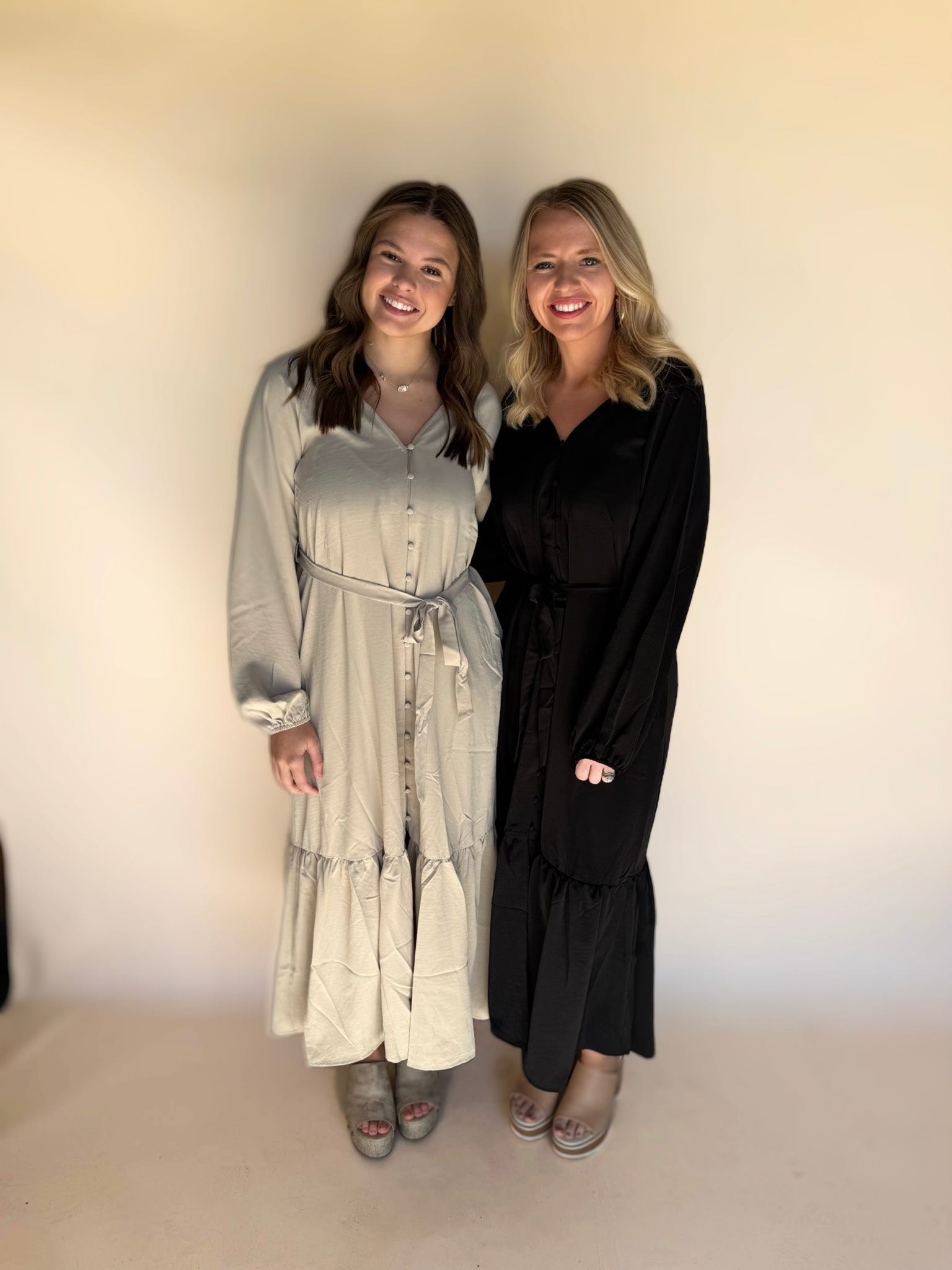 Two women standing side by side against a plain background