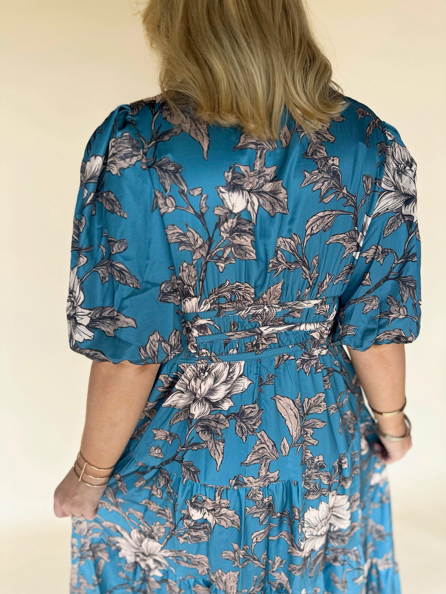 Woman wearing a blue floral dress against a beige background