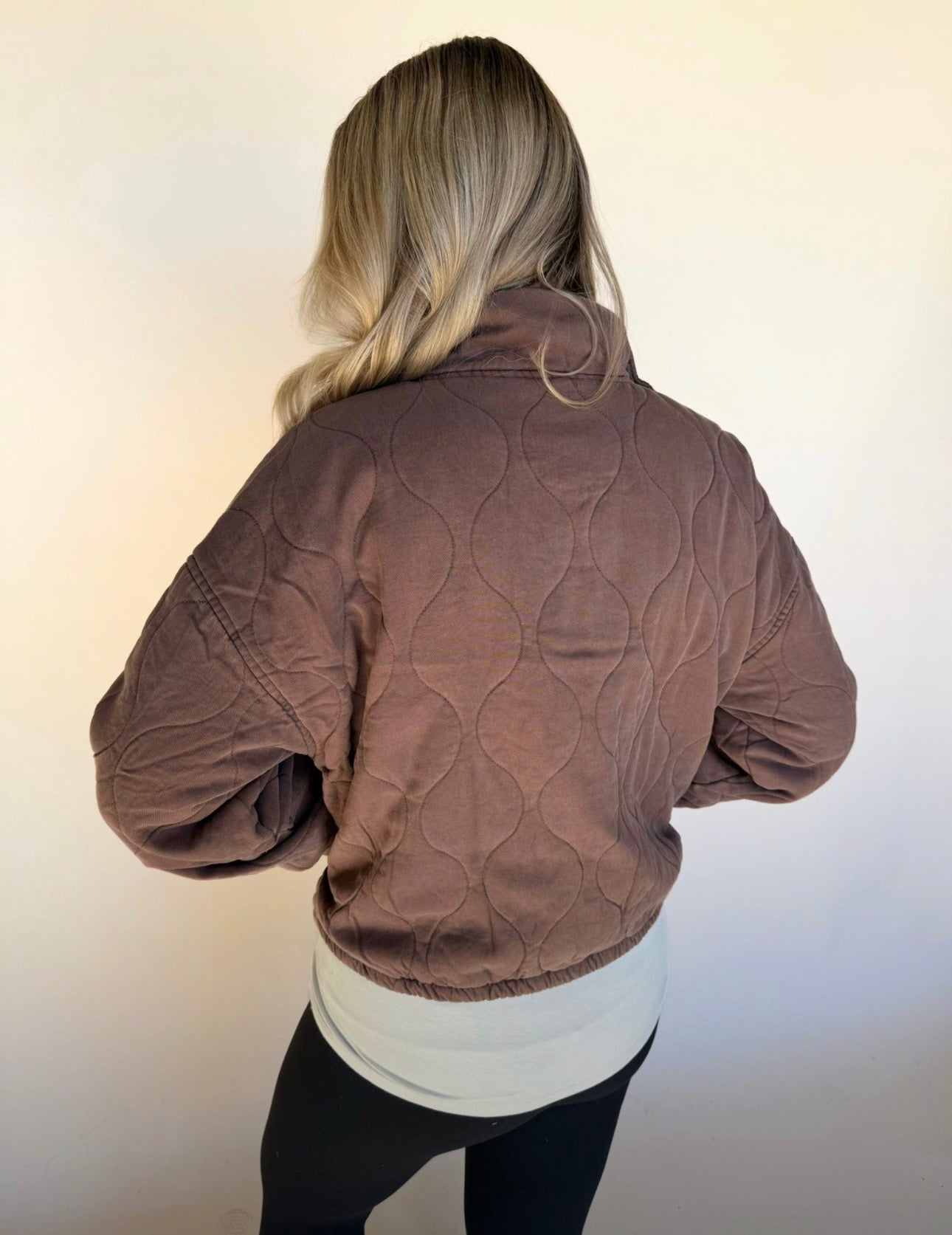 Person wearing a brown quilted jacket on a plain background
