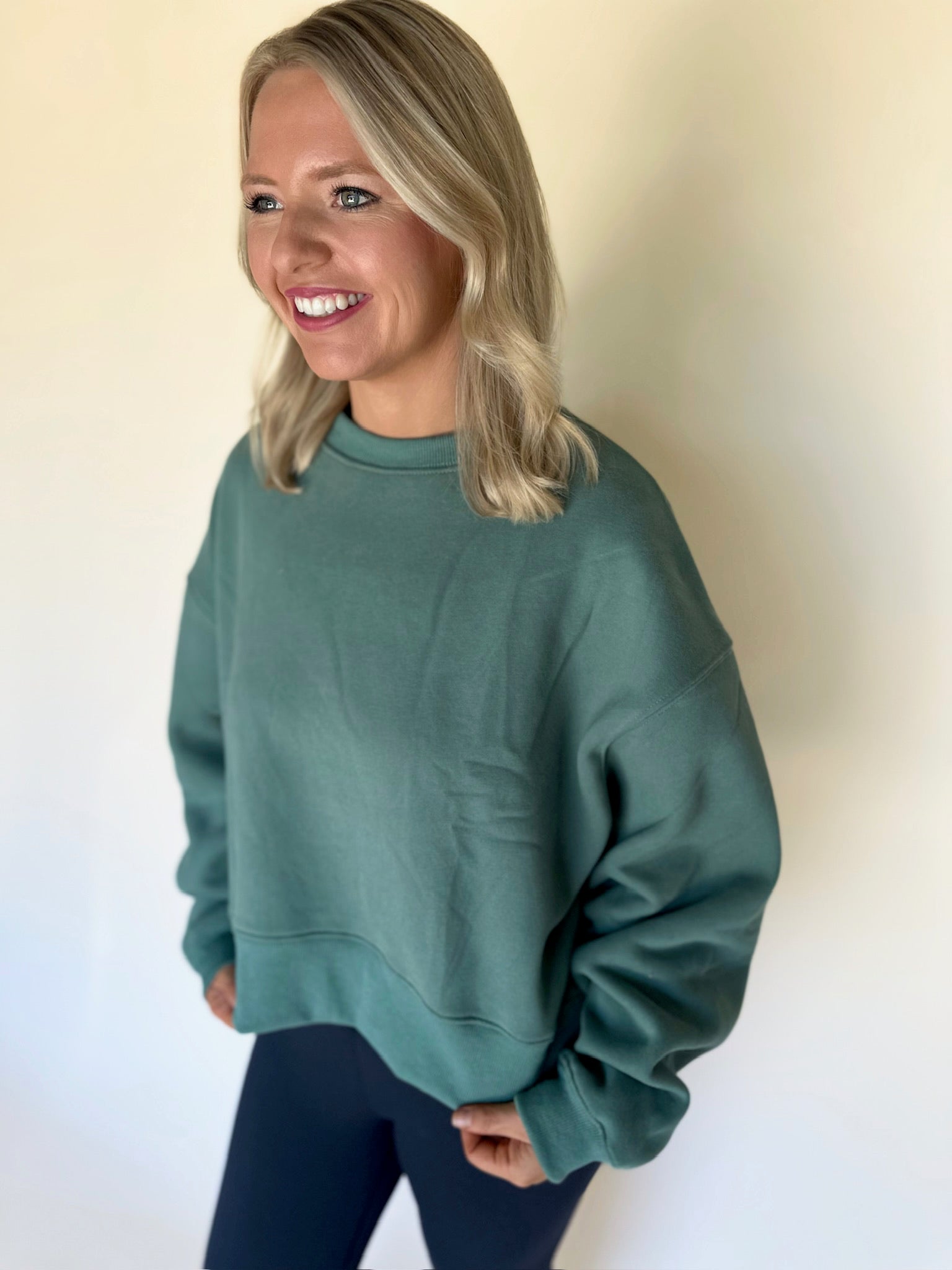 Woman wearing a green sweatshirt against a plain background