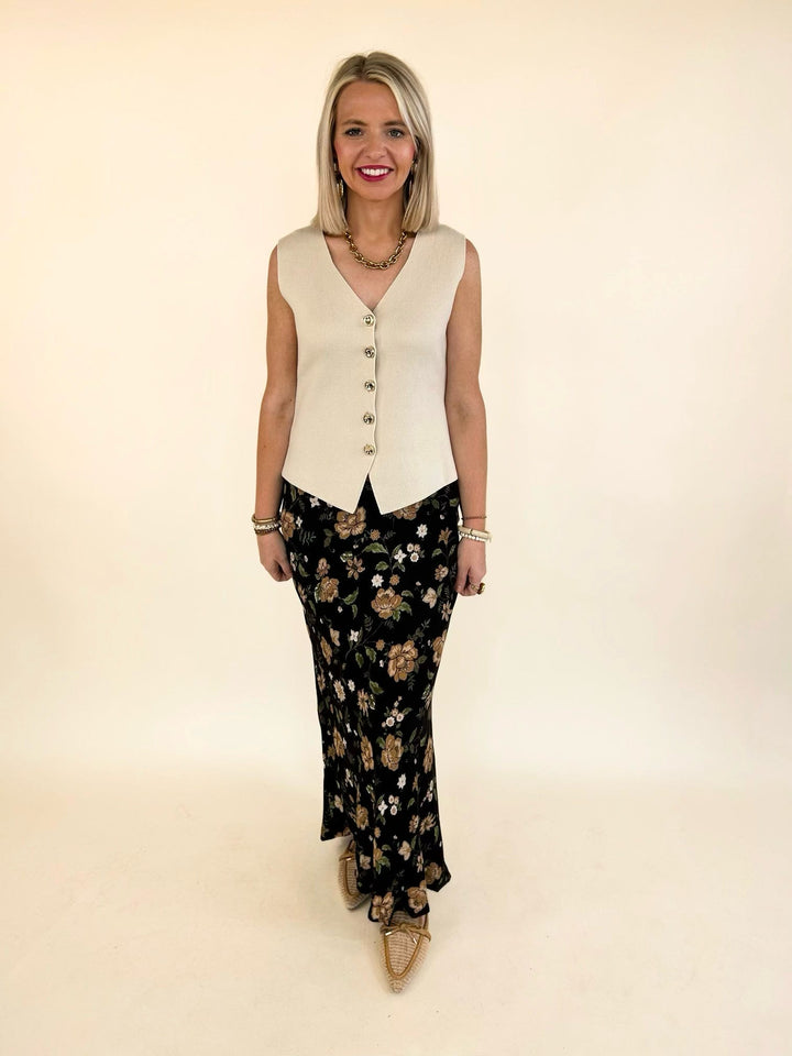 Model wearing the Elaina Floral Slip-On Midi Skirt with a sleeveless ivory sweater vest and pointed-toe flats.
