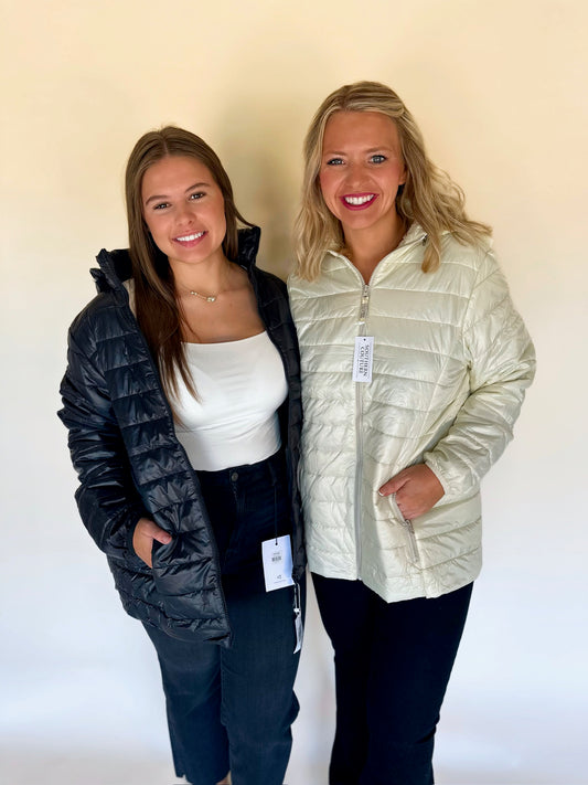Two women wearing puffer jackets against a plain background