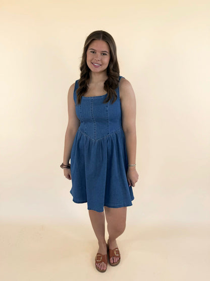 Woman wearing baby blue denim mini dress with scoop neckline and flowy skirt styled with brown sandals