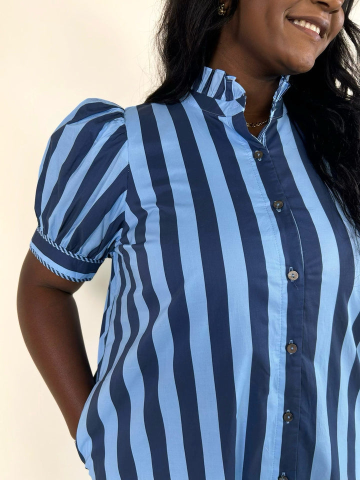 Close-up of the blue striped button-front midi dress highlighting the ruffle neckline, puff sleeve construction, and vertical stripe design.