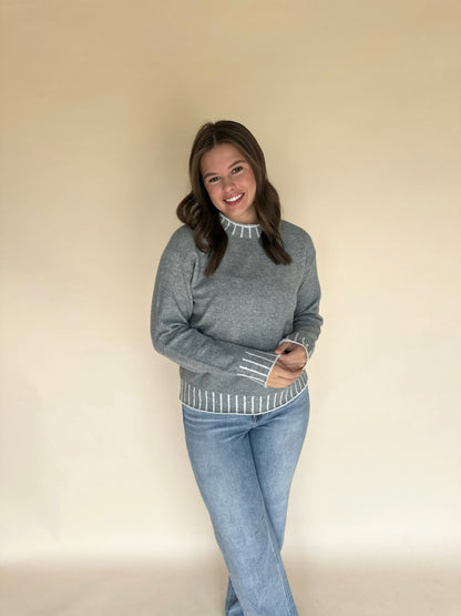 Woman wearing a light blue sweater and light blue jeans against a beige background
