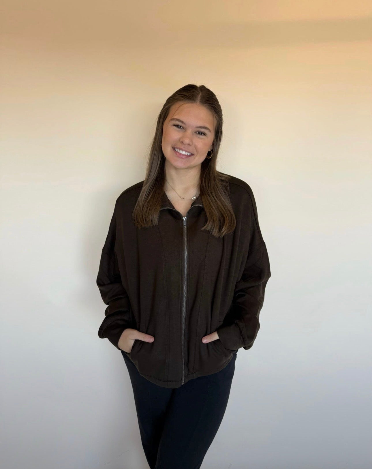 Person wearing a dark brown zip-up jacket against a plain background