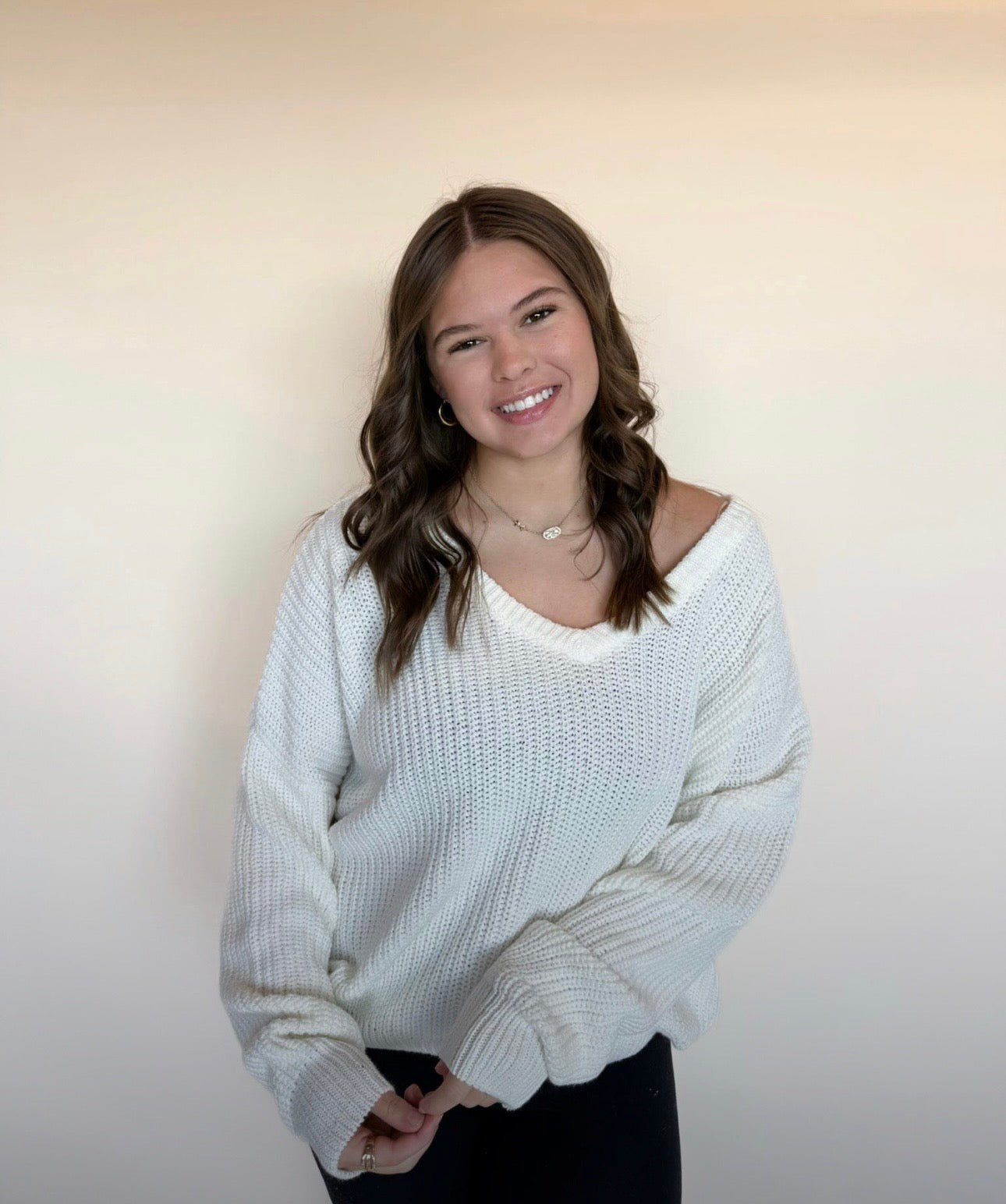 Woman wearing a white sweater against a plain background