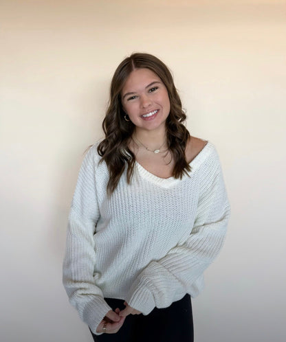 Woman wearing a white sweater against a plain background
