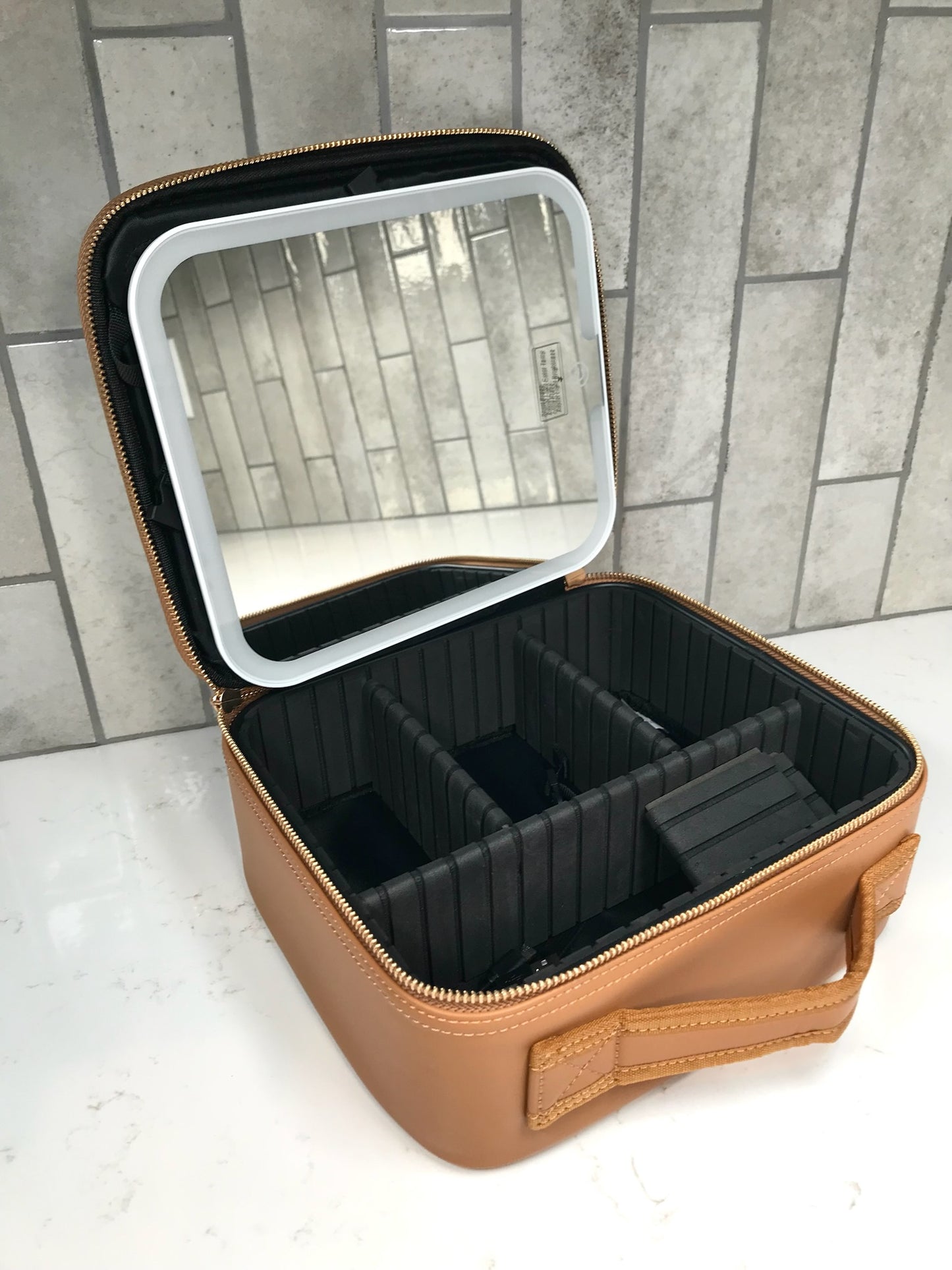 Brown makeup case with black interior and mirror on a tiled floor background