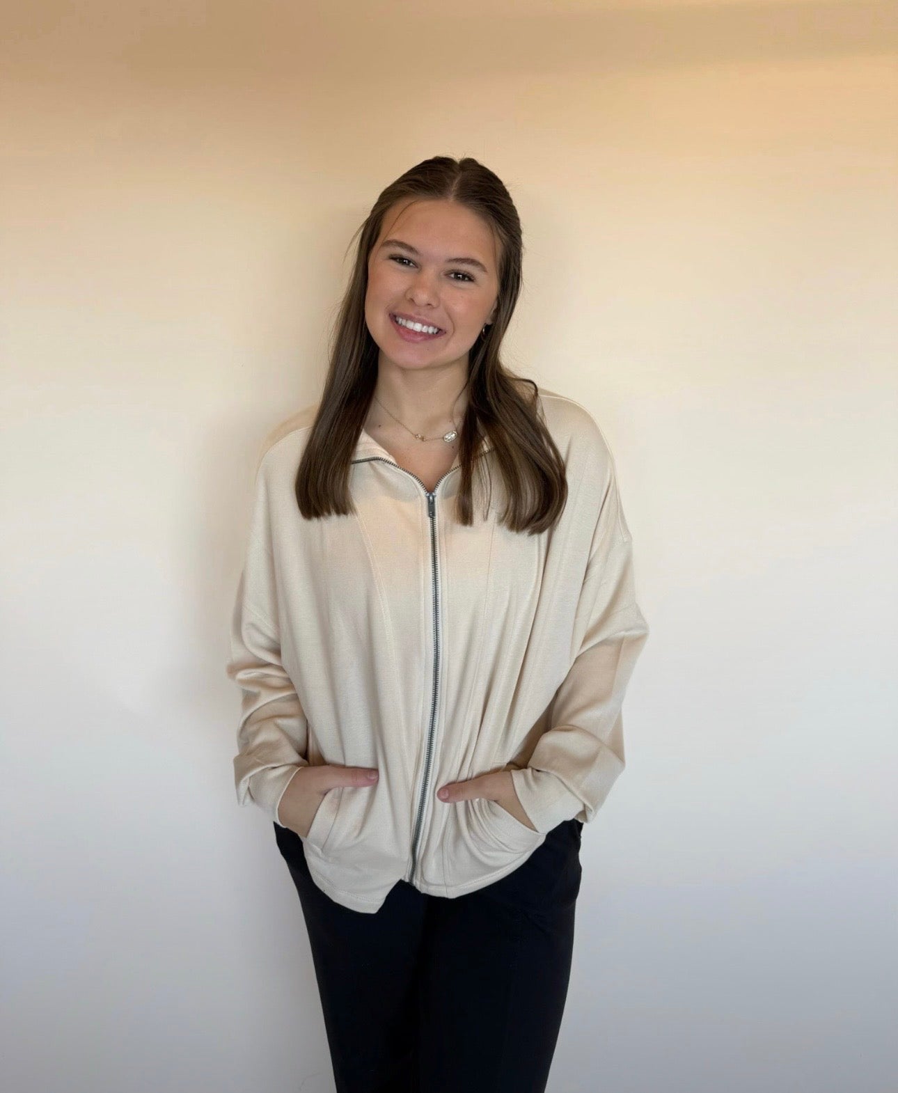 Woman wearing a beige blouse against a plain background