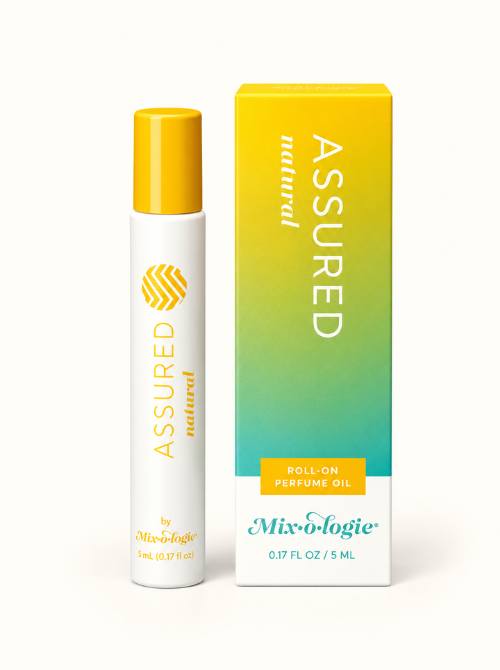 Mixologie Assured Natural 5 mL rollerball perfume oil with yellow cap and yellow-to-teal gradient fragrance box on a cream background.