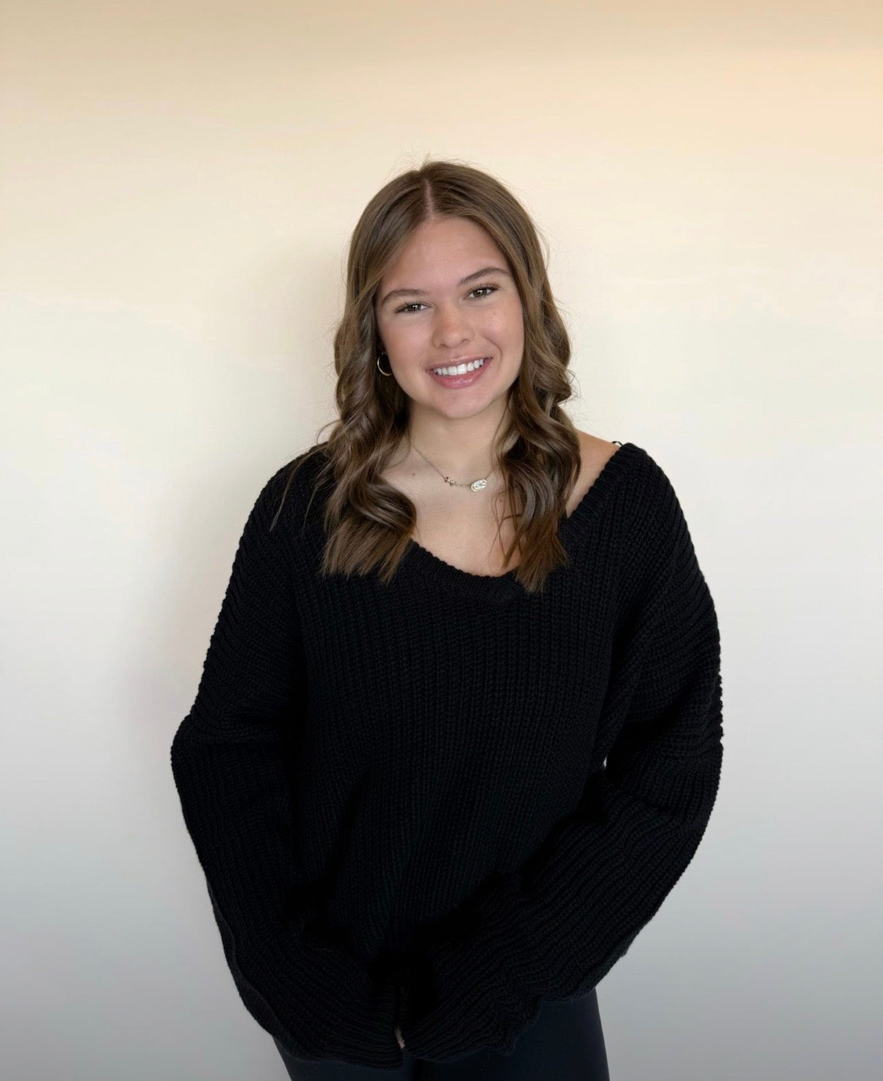 Person wearing a black sweater against a plain background