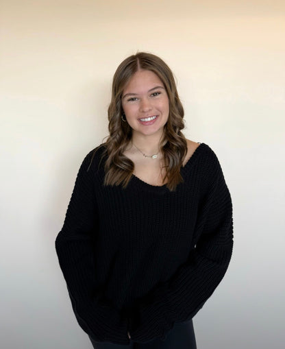 Person wearing a black sweater against a plain background