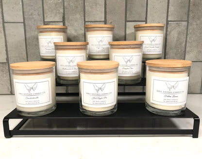 Set of candles with wooden lids on a black metal stand against a tiled wall.