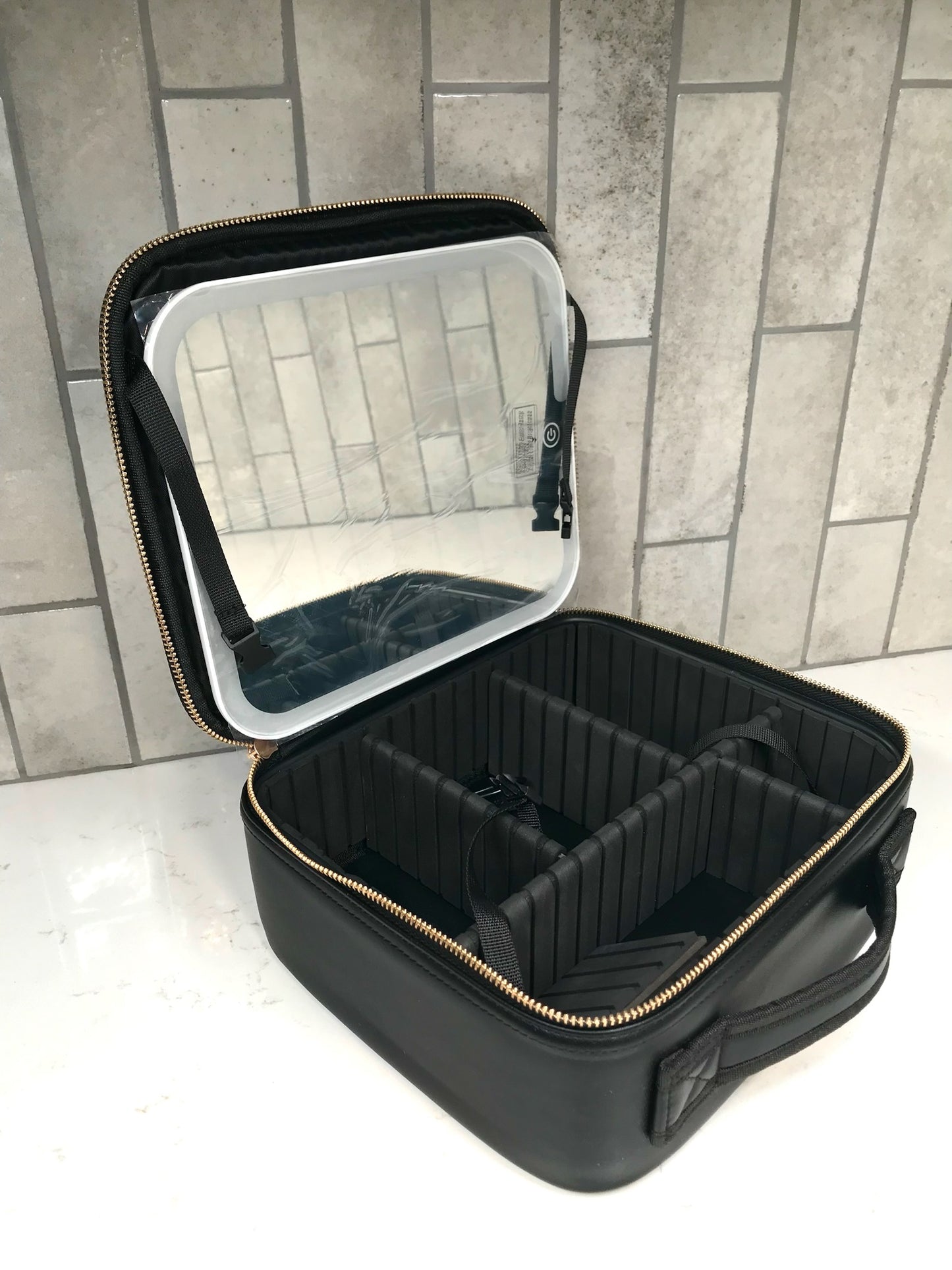 Black makeup case with mirror on a tiled floor