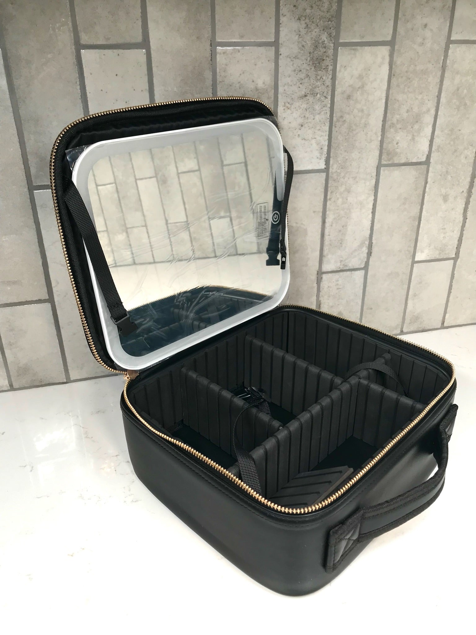 Black makeup case with mirror on a tiled floor