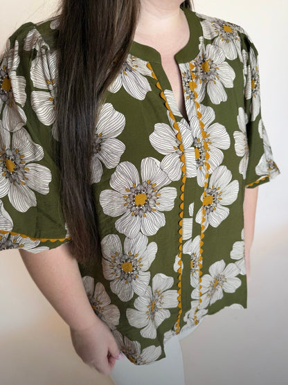 Woman wearing a green floral blouse with a plain background