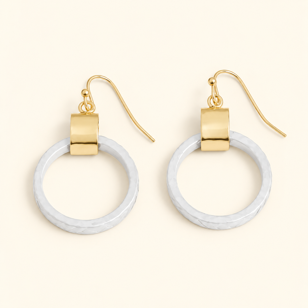 White textured circle drop earrings with gold-tone accents and fishhook closures, featuring a 2-inch dangle design on a cream background.