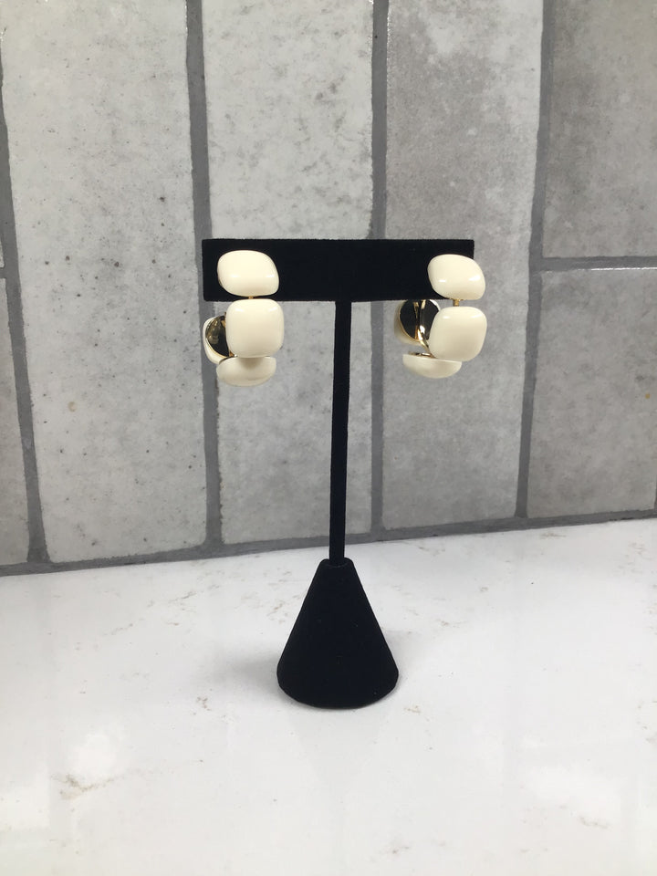 Cream linked acrylic square hoop earrings displayed on a black jewelry stand with gold accents.