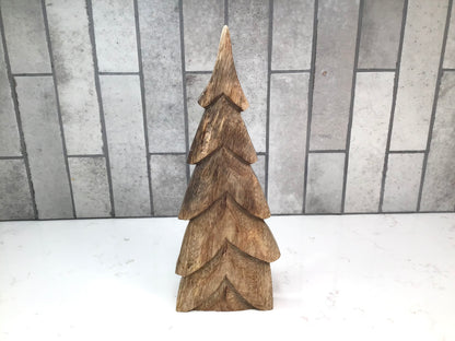 Wooden Christmas tree decoration on a white surface with a tiled wall background