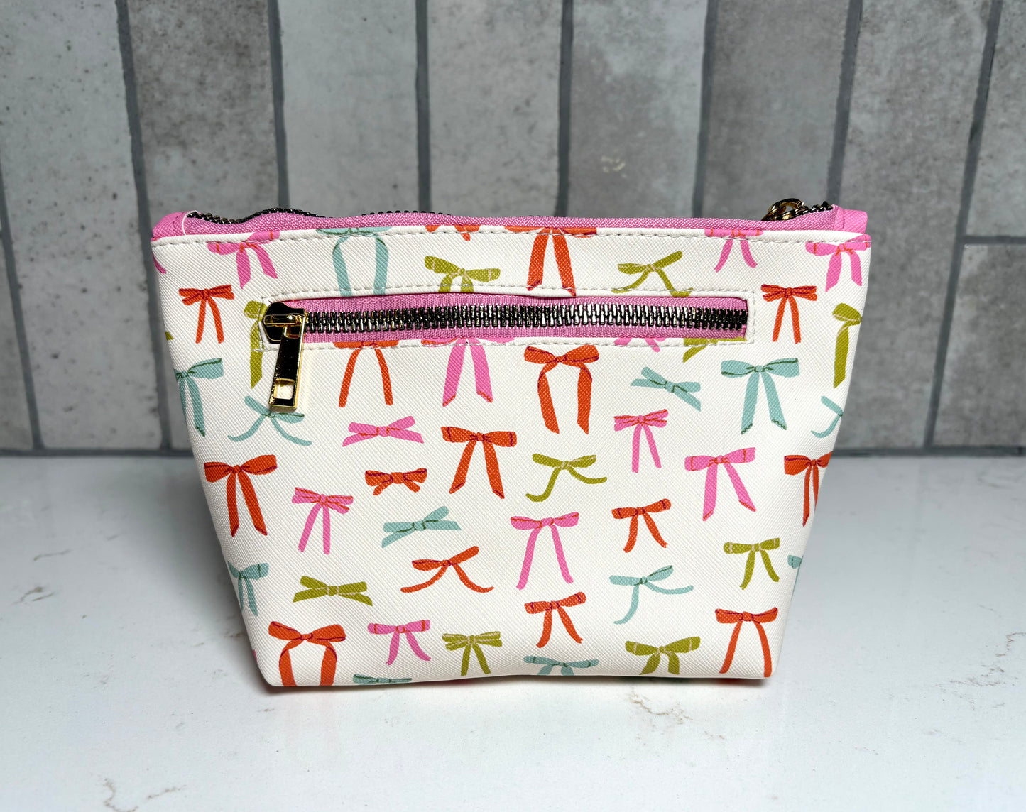 Bow print cosmetic pouch with back zipper pocket and gold hardware, colorful ribbon makeup bag