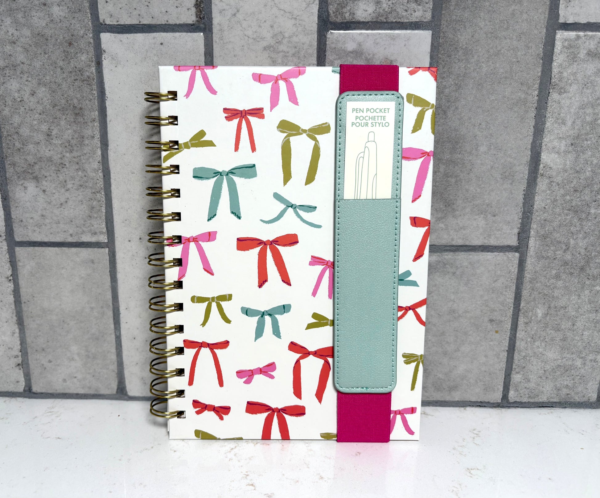 Colorful spiral bound bow print notebook with elastic closure and built-in pen pocket, ribbon pattern planner journal gift from Square 1 Boutique