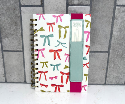 Colorful spiral bound bow print notebook with elastic closure and built-in pen pocket, ribbon pattern planner journal gift from Square 1 Boutique