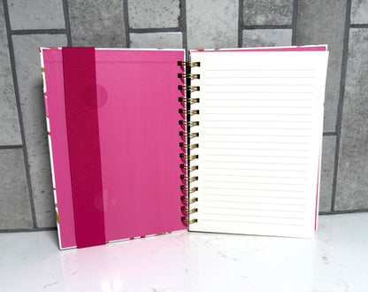 Open spiral bound notebook with lined pages, pink inside cover and elastic strap, colorful bow print planner journal gift from Square 1 Boutique