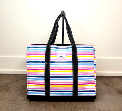 Original Deano Tote Large Bag in Stripe a Pose with colorful horizontal stripes, large reusable tote with black handles and structured bottom.