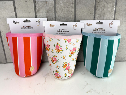 Three reusable insulated drink sleeves for 22–24 oz cups featuring pink and orange stripes, floral print, and green stripe designs, displayed on a countertop with gray tile background.