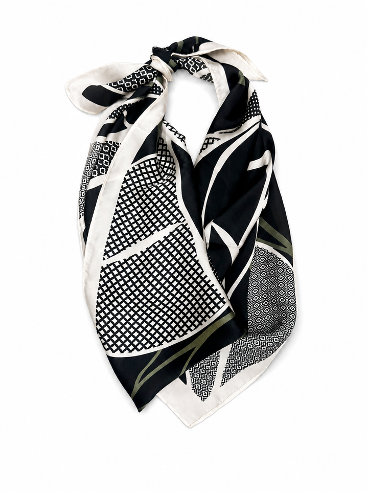 A square silk scarf with a black, white, and sage geometric pattern, tied in a knot against a plain white background.