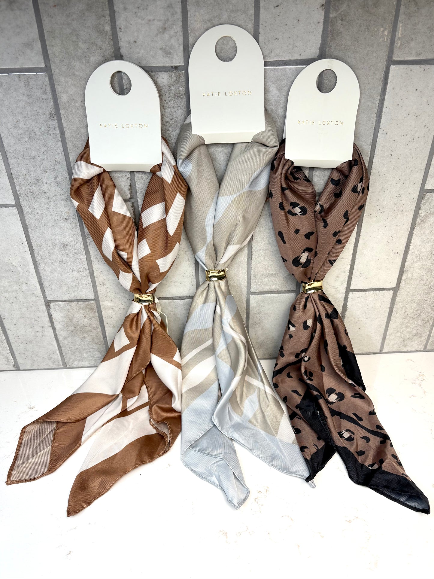 Katie Loxton Satin Multiway Scarf collection featuring ripple stripe, caramel checker, and mocha leopard prints.