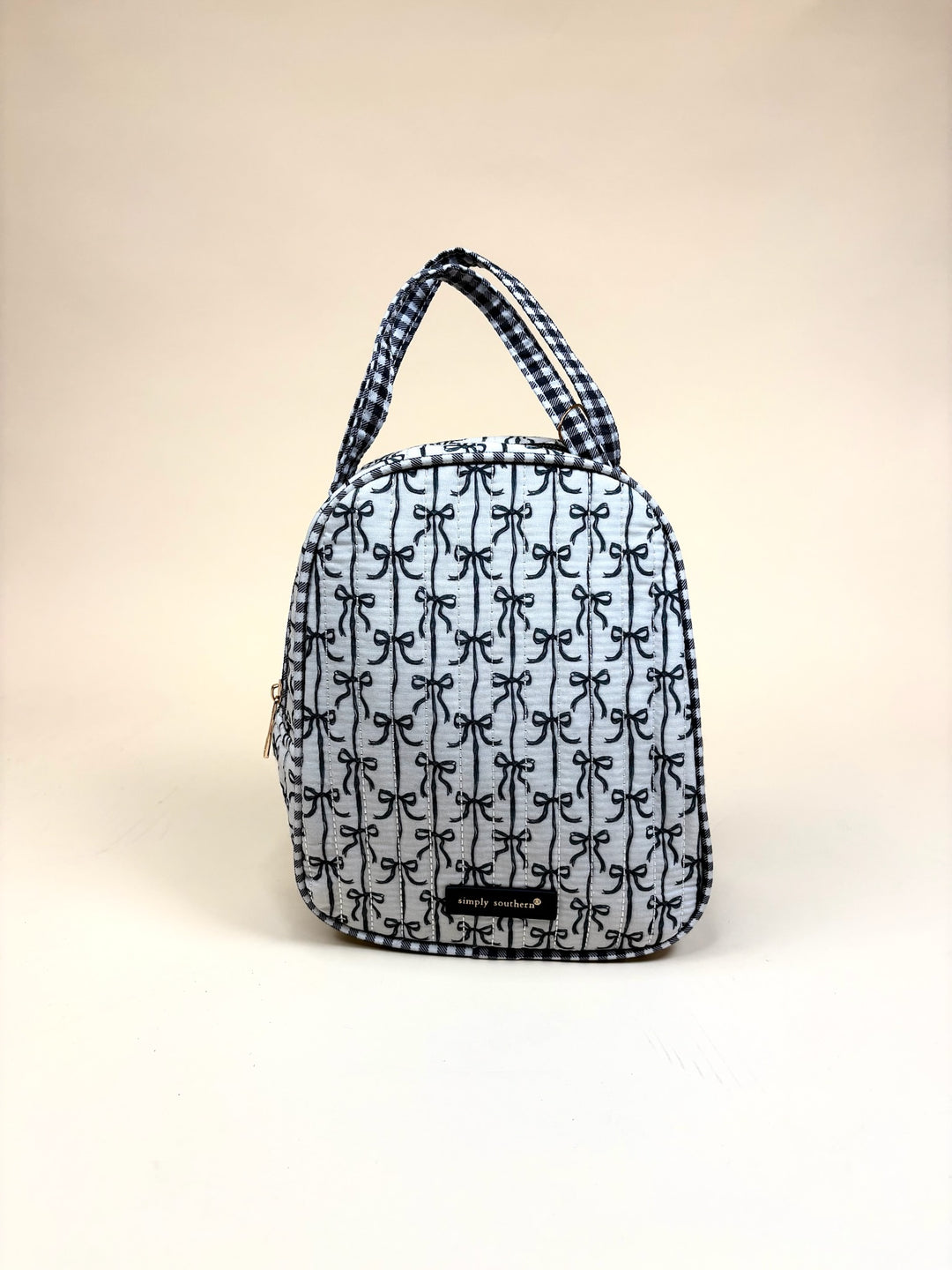 Simply Southern Black Bow Quilted Lunch Bag featuring an allover black bow print, quilted construction, dual carry handles, zip-top closure, and logo detail on a cream studio background.
